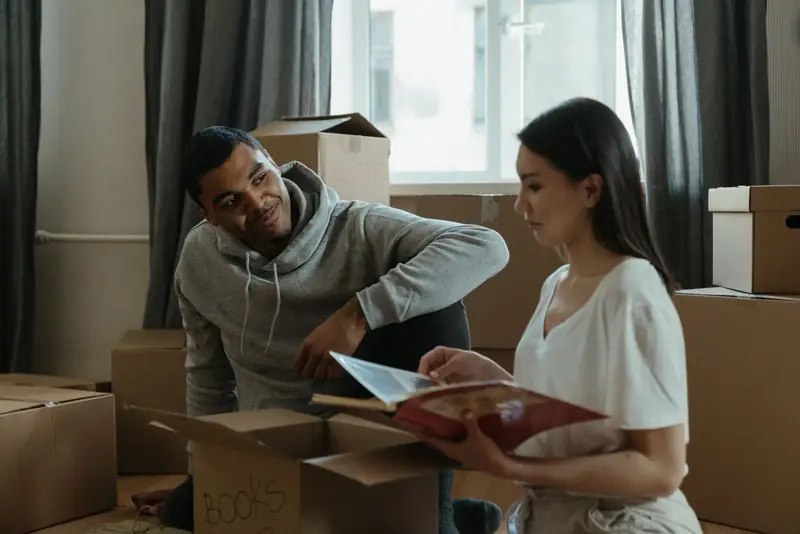 A couple unpacking boxes and looking at a photo album in their new home